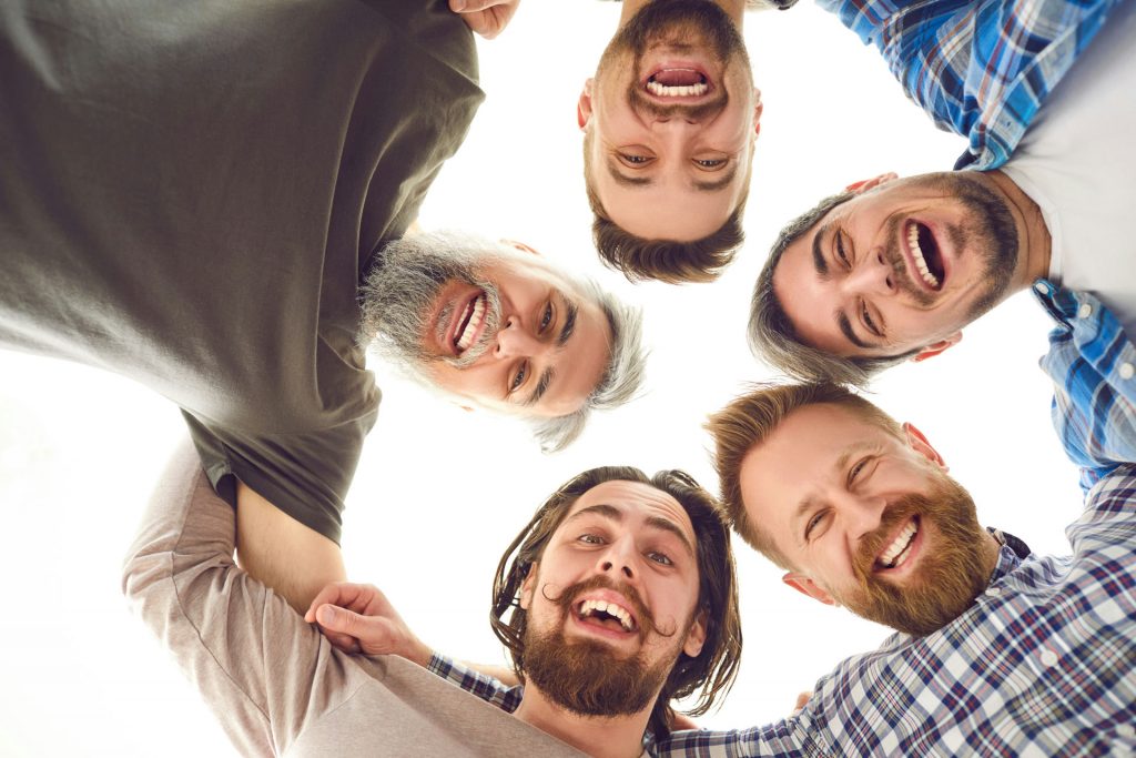 Friend group of five men looking down from a group hug