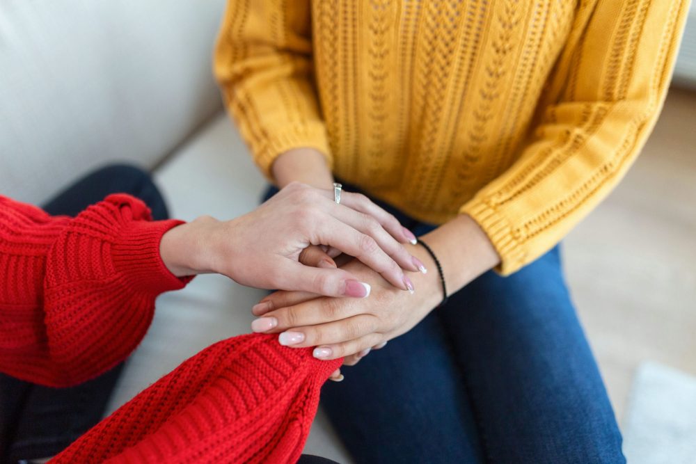 Therapist holding hand of woman to reassure her during individual therapy for addiction.
